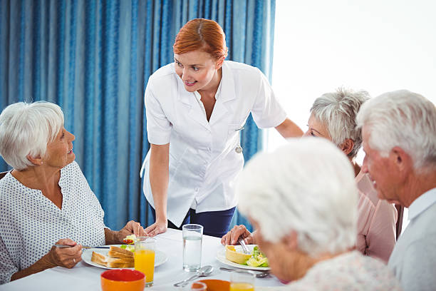 istock Smiling nurse looking at senior person during breakfast 614035420
