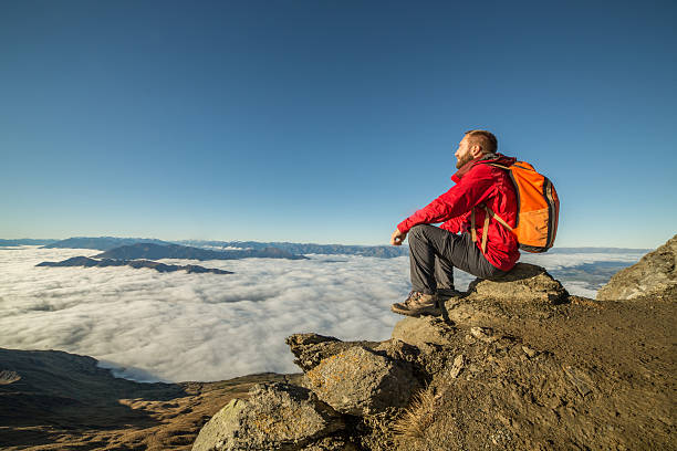 istock Young man hiking sits on a mountain summit 614037356
