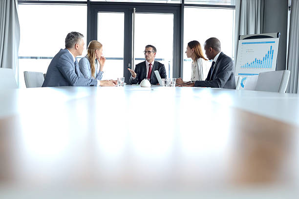 многоэтнические бизнесмены обсуждают за столом в зале заседаний - suit board room business businesswoman стоковые фото и изображения
