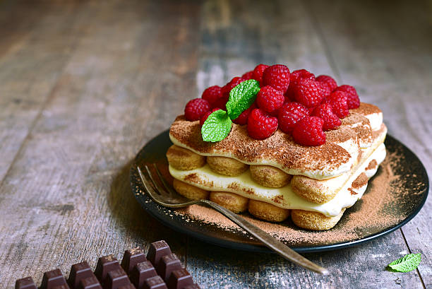 Creamy refreshing fruit cake with biscuits, vanilla cream, bananas and raspberries, decorated with white whipped cream. Served in cake trays