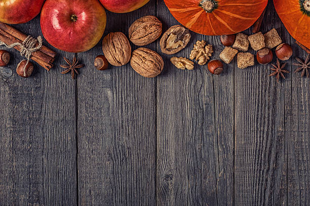 istock Wooden background with pumpkin, apples, nuts and spices. 614042028