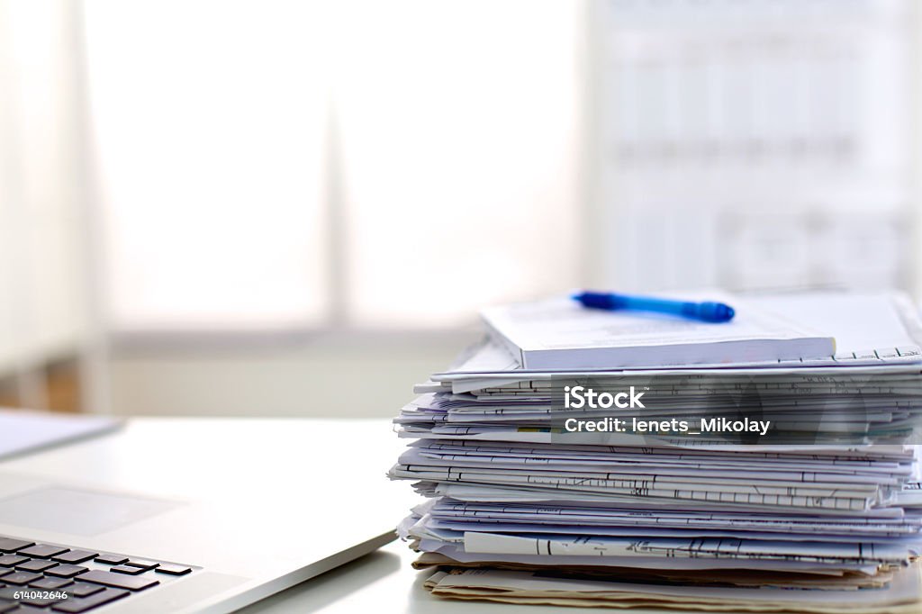 stack of papers on the desk with  computer a stack of papers on the desk with a computer. Deadline Stock Photo