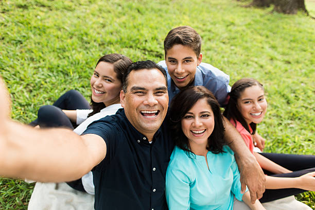 Happy latin familly taking a selfie outdoors A happy latin family of five taking a selfie and smiling in a horizontal medium shot outdoors. mexican ethnicity photos stock pictures, royalty-free photos & images