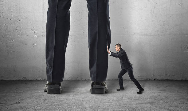 istock Little man pushes big feet. 614043698