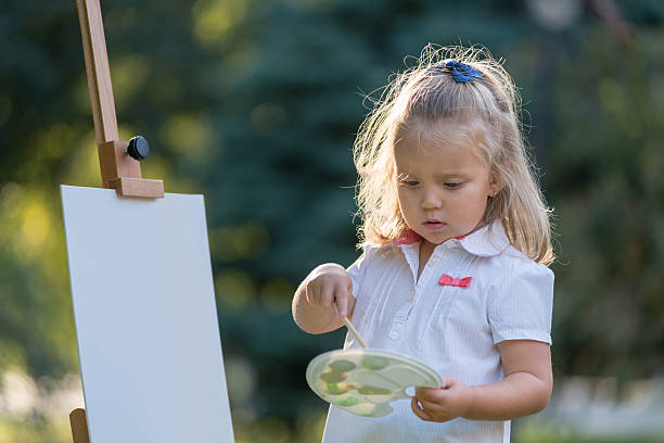 istock little girl draws paints 614045464