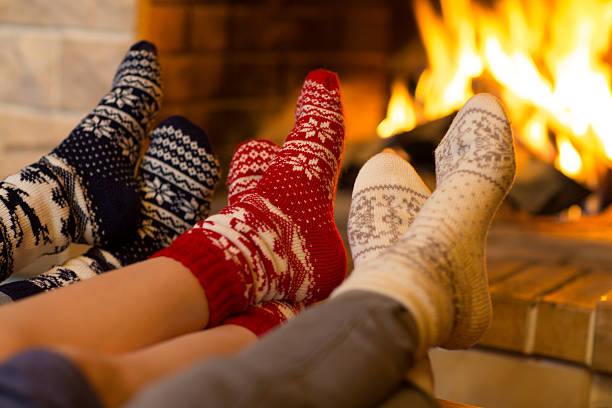 famille en chaussettes près de la cheminée en hiver ou à noël - feu de cheminée chaussette photos et images de collection