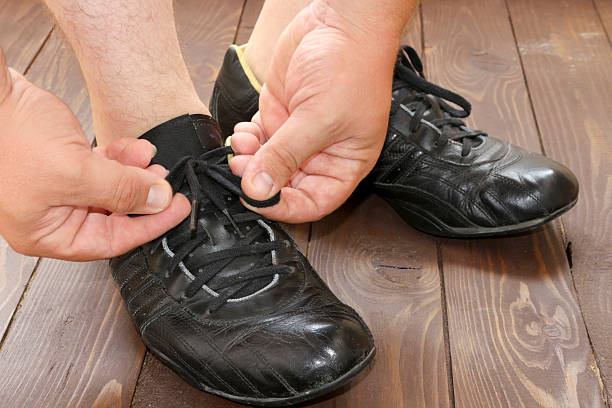 istock Tying Shoe laces a man sits on a wooden floor. 614047016