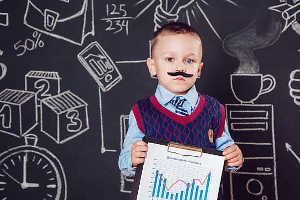istock Little boy as a businessman with mustache shows graph of 614047620
