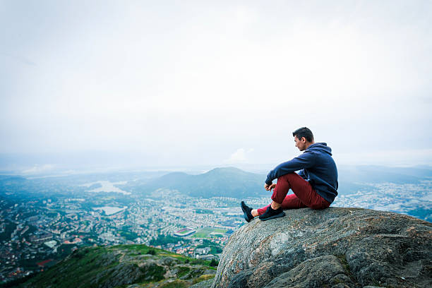 istock Tourist sit on cliff's edge and looking to valley 614047928