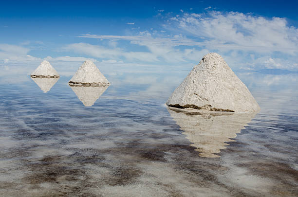 istock cone shaped salt mounds on salt flats, reflected in water 614048040