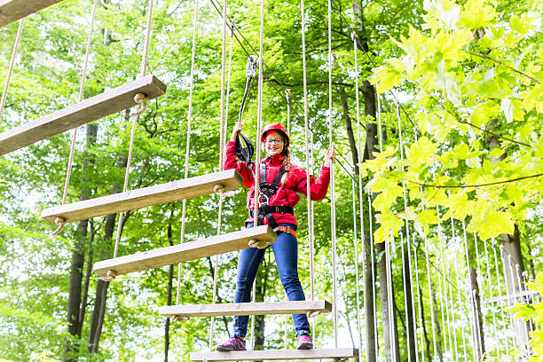 istock Kid walking on rope bridge in climbing course 614049642