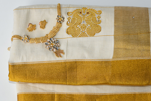 Traditional handmade white silk sari / saree with golden details, woman use to wear on Onam, Vishu festival Kerala India. gold oriental, authentic indian jewellery ornaments