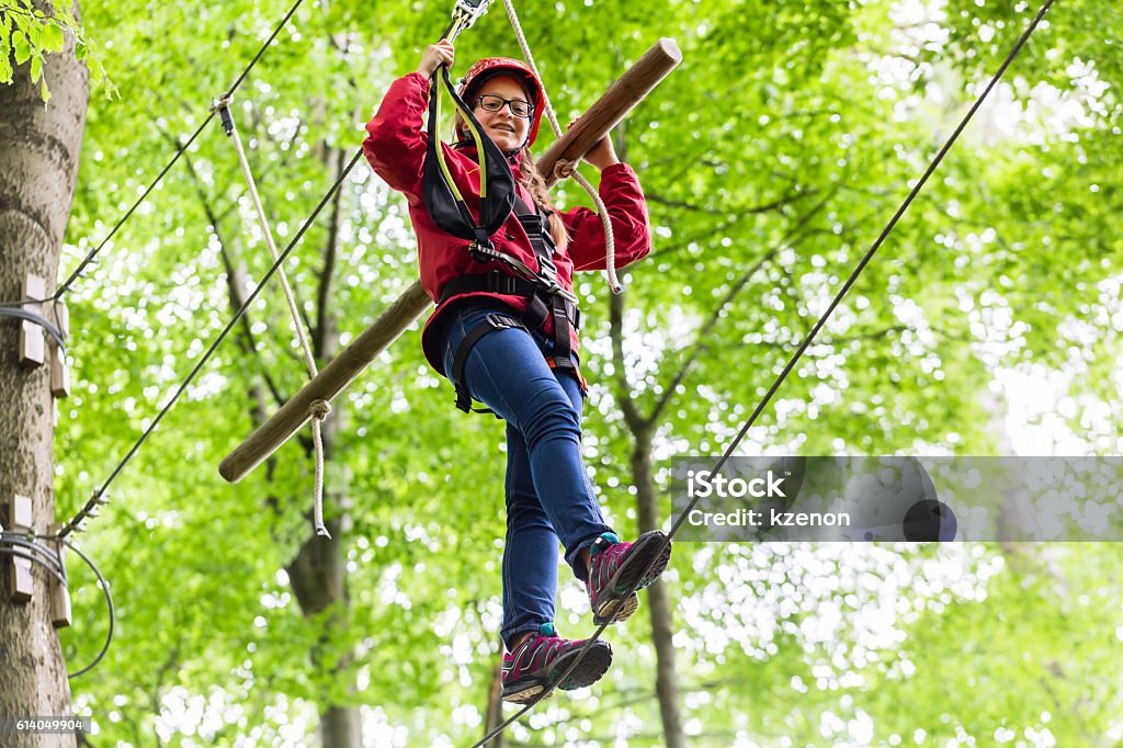 Child reaching platform climbing in high rope course Activity Stock Photo