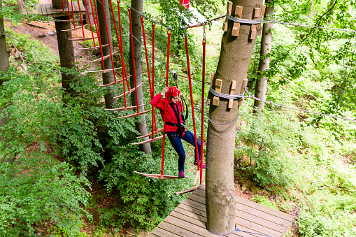Girl seen from above climbing in high rope course