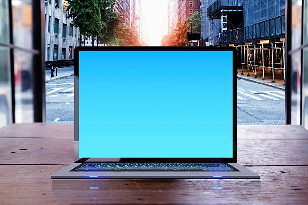 laptop computer on wooden desk in coffee shop, Street at sunset seen in the background.