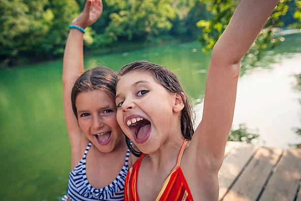 Two happy girls with outstretched arms by the river