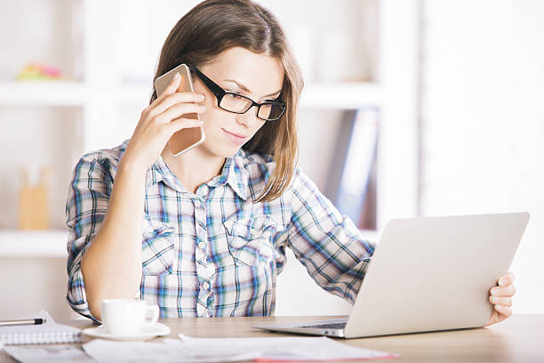 istock Woman on phone using laptop 614057558