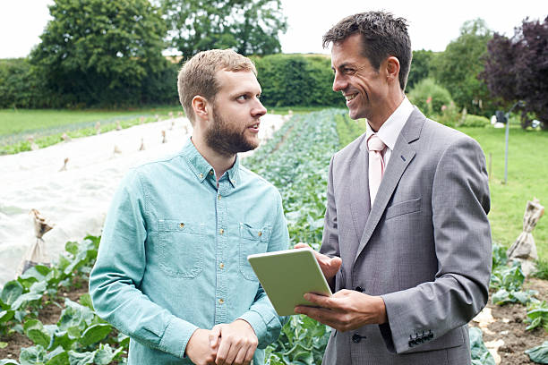 Businessman Using Digital Tablet During Meeting With Farmer In Field