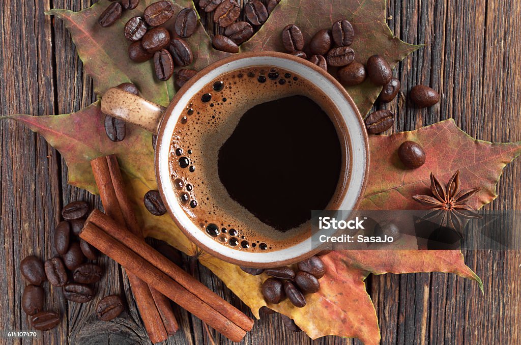 Cup of coffee Cup of hot coffee and autumn maple leaves on old wooden background, top view Anise Stock Photo