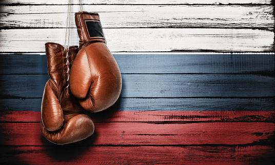 Boxing gloves hanging on wooden wall with Russian flag