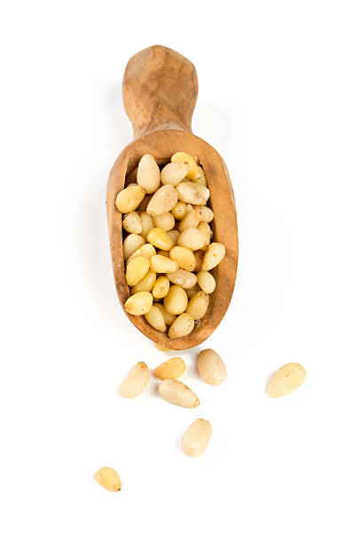 istock pine nuts in a wooden scoop isolated on white background 614110288