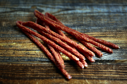 Closeup of dried sticks sausages on a wooden board