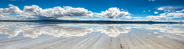 塩の平地の地平線に収束するトラックのパノラマ - ウユニ塩湖 ストックフォトと画像
