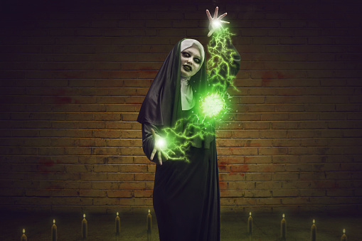 Scary devil nun for halloween concept image. She is casting satanic spell