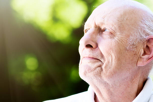 istock Old man with eye trouble squints up at sun 614127596