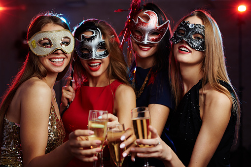 Girls in masks toasting with champagne at party
