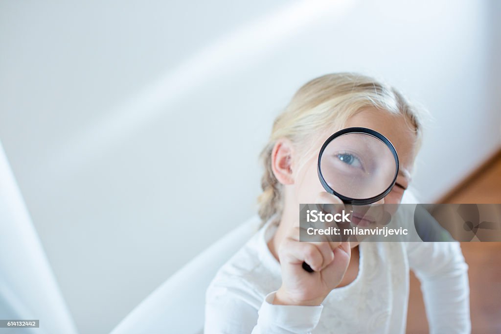Little girl looking through a magnifying glass Schoolgirl. Shallow DOF. Developed from RAW; retouched with special care and attention; Small amount of grain added for best final impression. 16 bit Adobe RGB color profile. Child Stock Photo