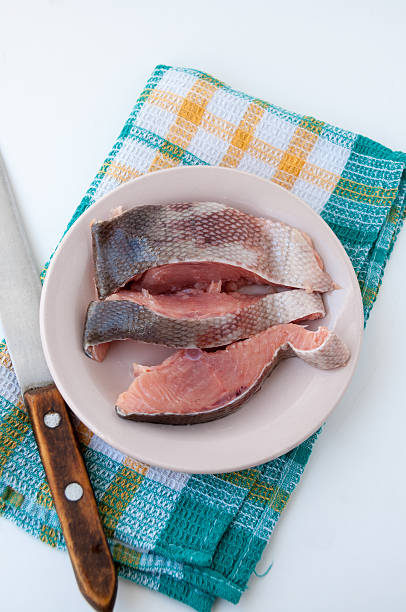 At checkered napkin lay plate with raw fish and knif At the checkered napkin lay a plate with raw red fish and a knife knif stock pictures, royalty-free photos & images