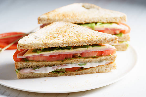 ham sandwich Sandwich of whole wheat bread with ham, cheese and fresh tomato, triangle cut, three layers sandwich bread sandwich healthy lifestyle healthy eating bread stock pictures, royalty-free photos & images