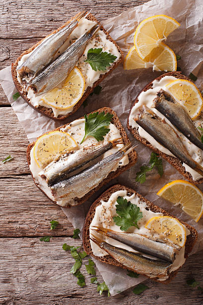 istock Toasts with sprats, cream cheese and lemon close-up. Vertical 614136706