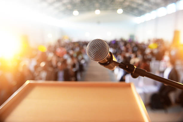 Microphone in front of podium with crowd in the background A waiting crowd in front of a microphone and podium lectern stock pictures, royalty-free photos & images