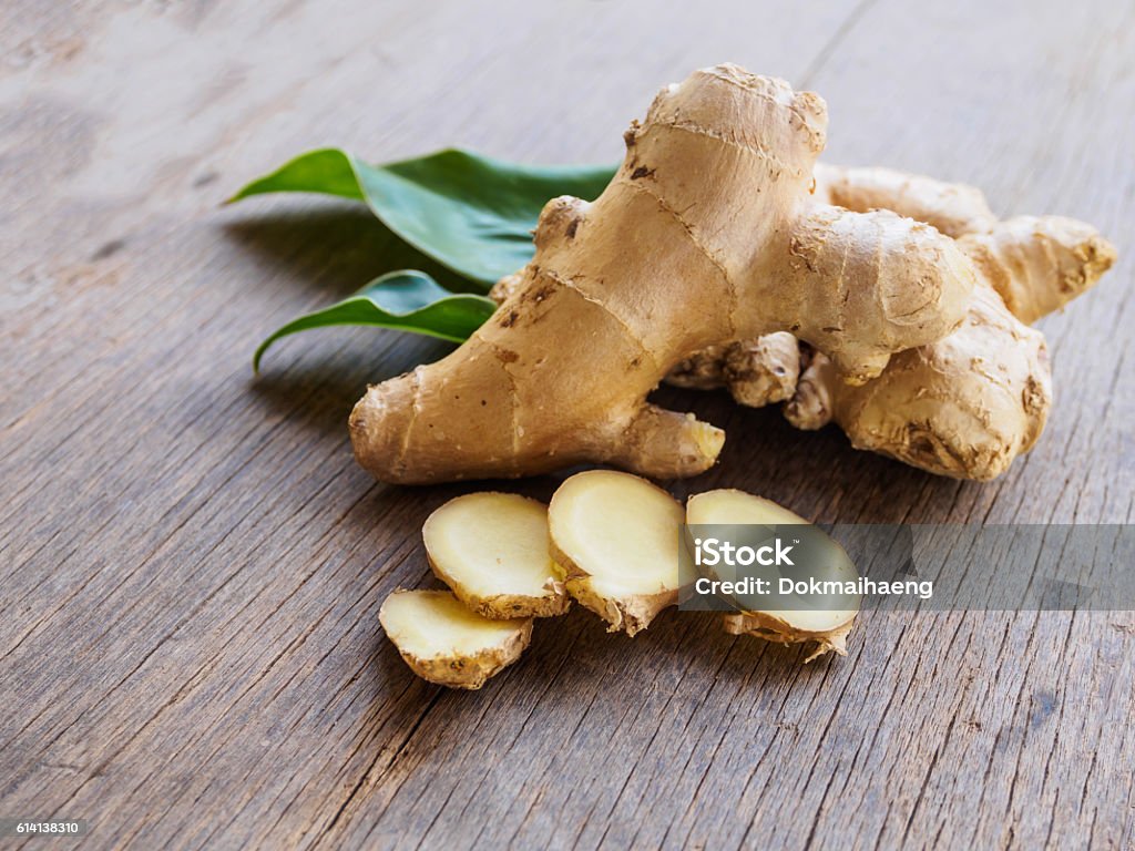 Ginger root slice with leaf and has a spicy taste Ginger root slice with leaf and has a spicy taste on wooden background Ginger - Spice Stock Photo