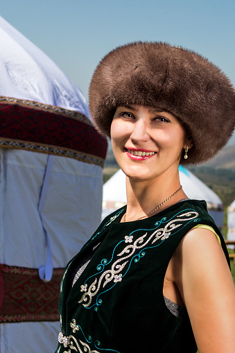 Kazakh girl in national clothes standing near the yurt