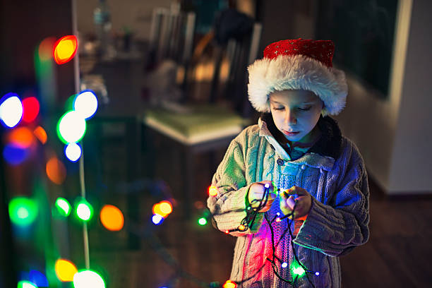istock Little boy decorating room with christmas lights 614142354