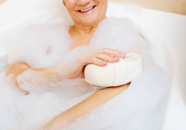 mujer que se baña relajándose con esponja - bathtub women naked human face fotografías e imágenes de stock