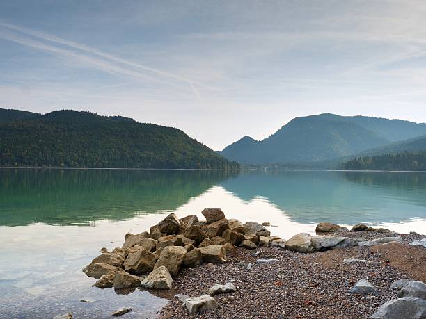 istock Big boulders sticking out from smooth lake water level. 614144344