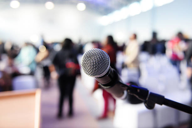 istock Microphone in front of podium with crowd in the background 614145254