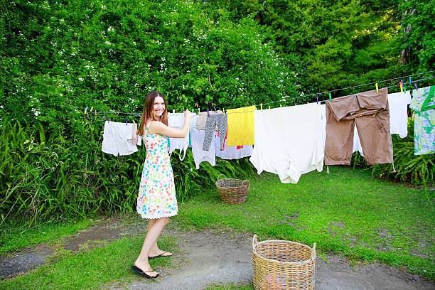 istock Smiling young woman hanging laundry on clothesline at the backyard 614147264