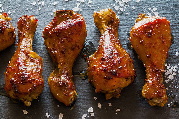 istock Roasted chicken drumsticks on black background. Top view. 614148236