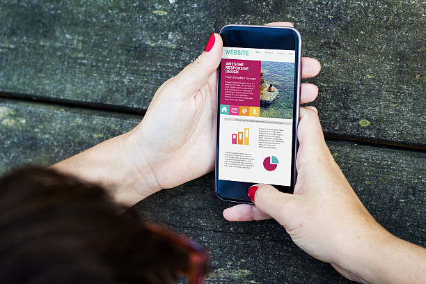 top view of woman using smartphone to check fresh designed responsive website. All screen graphics are made up.