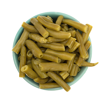 Top view of a serving of organic cut green beans in a small bowl isolated on a white background.