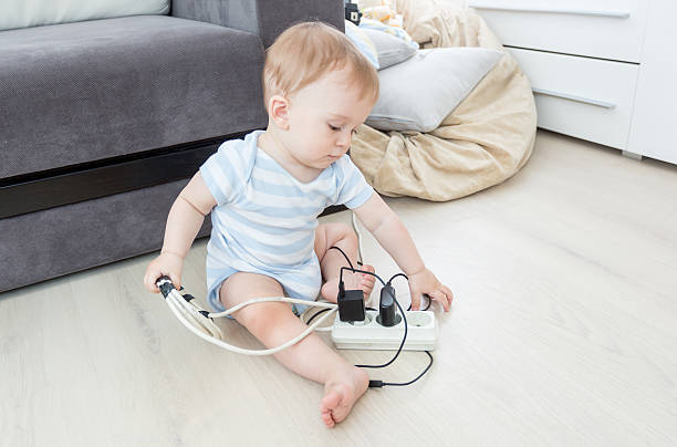 電気延長とワイヤーで遊んで愛らしい赤ちゃん - electric plug outlet pulling electricity ストックフォトと画像