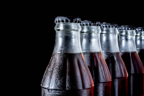 Soda glass bottles standing in a row isolated Soda glass bottles standing in a row isolated on a black background soda bottle stock pictures, royalty-free photos & images