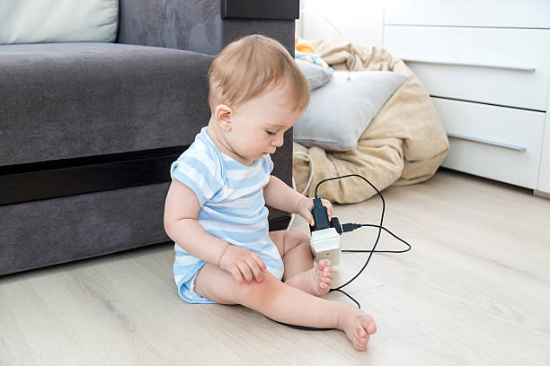 bebé sentado solo y jugando con cables eléctricos - living dangerous fotografías e imágenes de stock