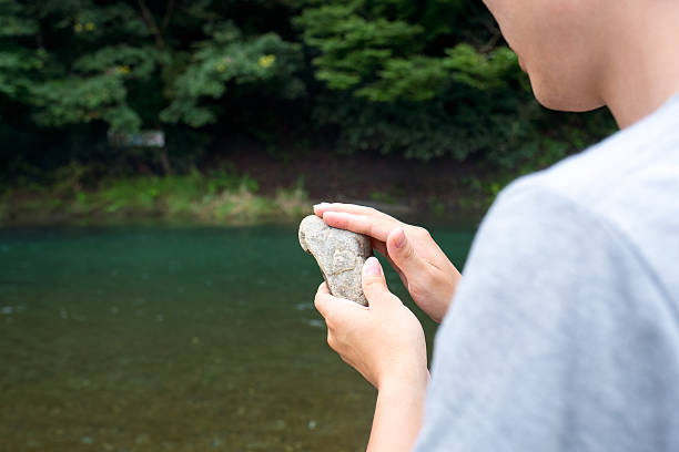 istock Man holding a stone by the river 614205296