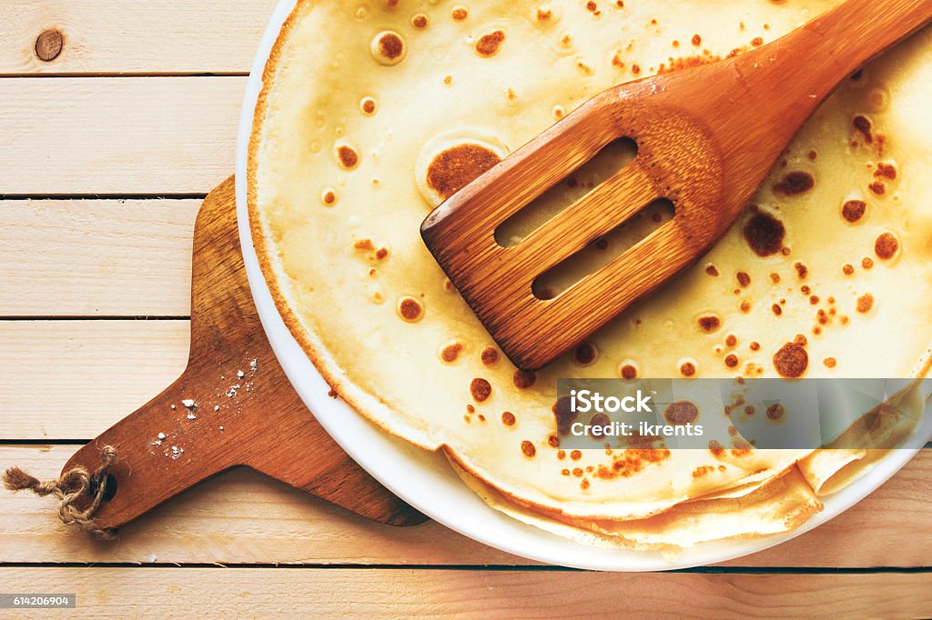 The cooked pancakes on plate on wooden table The cooked pancakes on plate on wooden table with wooden kitchenware Breakfast Stock Photo